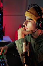 Discord Nitro, Was es bringt und was es kostet, Gaming Eine Person mit Headset auf dem Kopf sitzt vor einem Gaming-Rechner.