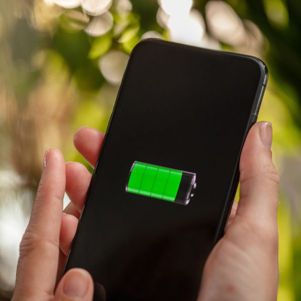 Eine Person h&auml;lt ein Smartphone mit der Anzeige von einer fast voll geladenen Batterie in der Hand.