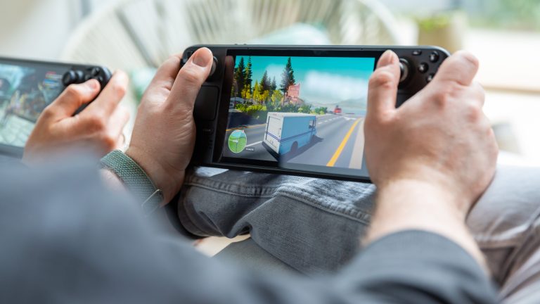 Eine Person spielt etwas auf einem Steam Deck LCD, daneben h&auml;lt jemand ein Steam Deck OLED in der Hand.
