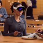 Eine Person hat in einem Apple Store die Vision Pro auf dem Kopf. Daneben steht ein*e Apple-Mitarbeiter*in mit einem iPad in der Hand.