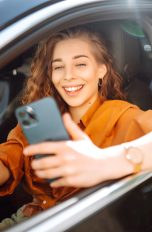 Apple CarPlay funktioniert nicht, Probleme und ihre Lösungen Eine Person sitzt in einem Auto und hält ein iPhone in der Hand.