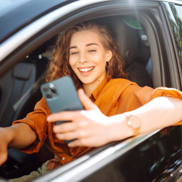 Eine Person sitzt in einem Auto und h&auml;lt ein iPhone in der Hand.