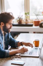 Eine Person sitzt an einem Schreibtisch vor einem MacBook Pro.