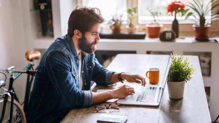 Eine Person sitzt an einem Schreibtisch vor einem MacBook Pro.
