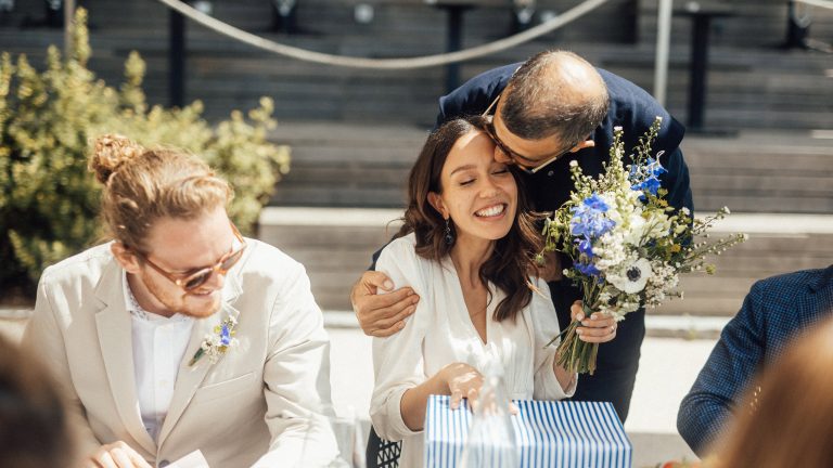 Ein Hochzeitsp&auml;rchen sitzt an einem Tisch und nimmt ein Geschenk in Empfang.