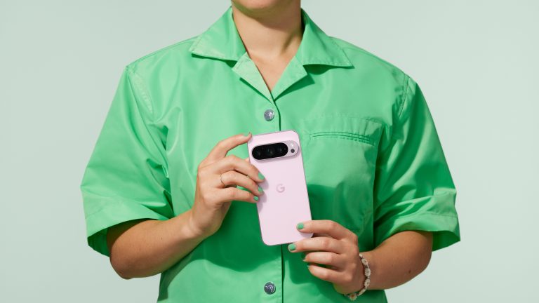 Eine Person mit grünem Hemd hält ein pinkes Google Pixel 9 Pro in der Hand.