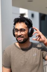 Sonos Ace und Apple AirPods Max, Modische Kopfhörer im Vergleich Eine Person steht draußen im Sonnenschein und trägt die Sonos Ace auf dem Kopf.