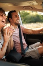 Apps für Android Auto, Praktische Programme für die Fahrt Zwei Personen sitzen in einem Auto und lachen während der Fahrt.