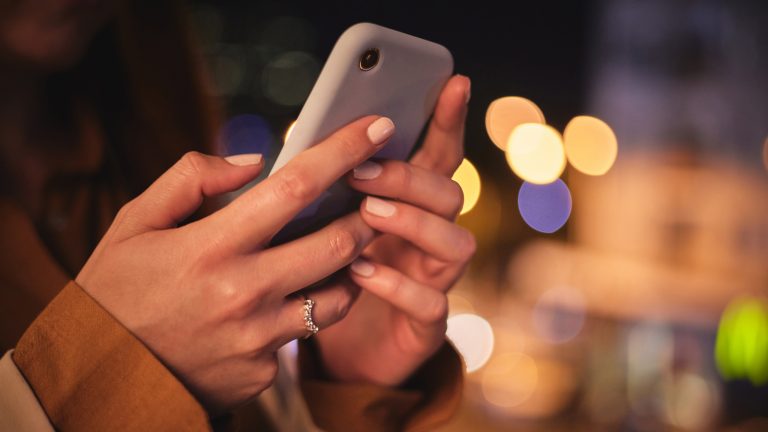 Nahaufnahme von den H&auml;nden einer Person, die ein Smartphone darin h&auml;lt.