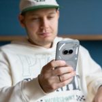 Eine Person sitzt und h&auml;lt ein Nothing Phone 2(a) Plus in der Hand.