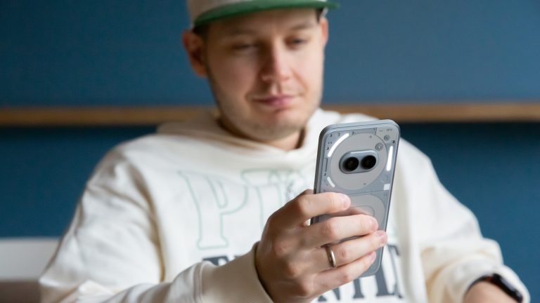 Eine Person sitzt und h&auml;lt ein Nothing Phone 2(a) Plus in der Hand.