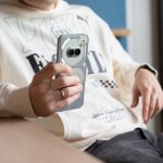 Eine l&auml;ssig sitzende Person h&auml;lt ein Nothing Phone 2(a) Plus in der Hand.