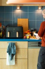 Eine Person schneidet in eine rK&uuml;che Fr&uuml;chte, neben ihr ist ein Airfryer von Philips zu sehen.)