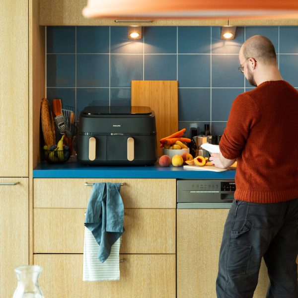 Eine Person schneidet in eine rK&uuml;che Fr&uuml;chte, neben ihr ist ein Airfryer von Philips zu sehen.)