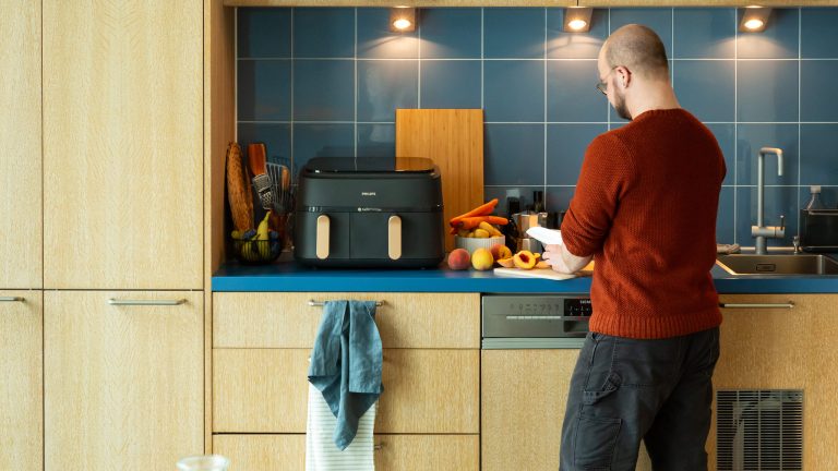 Eine Person schneidet in eine rK&uuml;che Fr&uuml;chte, neben ihr ist ein Airfryer von Philips zu sehen.)