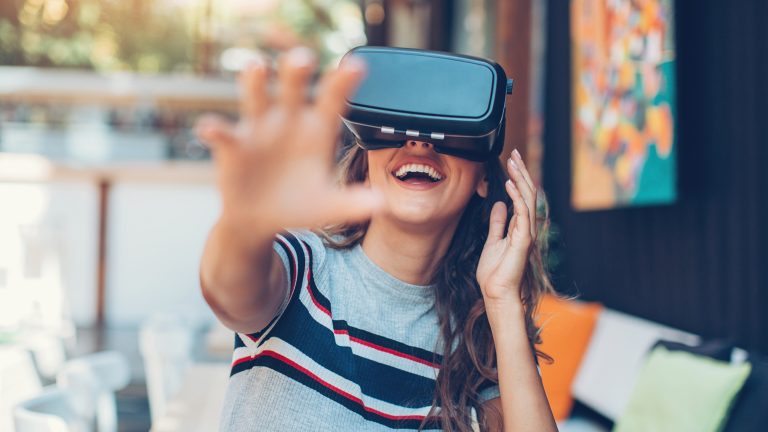 Eine Person vor einem Haus tr&auml;gt eine VR-Brille und scheint Spa&szlig; zu haben.