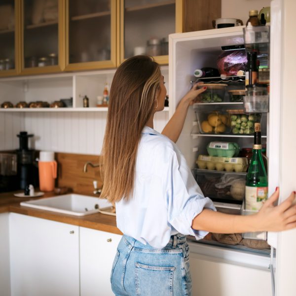 Eine Person nimmt etwas aus einem Einbauk&uuml;hlschrank heraus.
