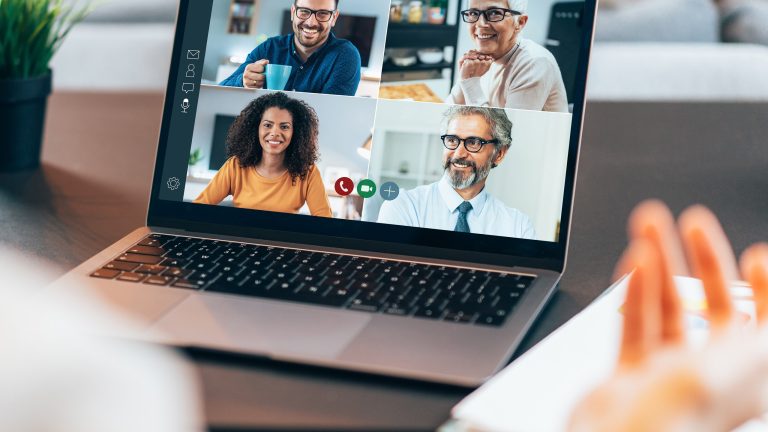 Eine Person sitzt vor einem ge&ouml;ffneten Laptop und ist in einem Meeting.