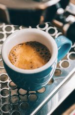 Kaufguide für kleine Siebträgermaschinen für Single-Haushalte Nahaufnahme einer blauen Espresso-Tasse auf dem Gitter einer Siebträgermaschine.