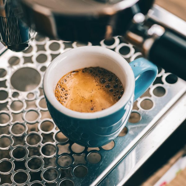 Nahaufnahme einer blauen Espresso-Tasse auf dem Gitter einer Siebtr&auml;germaschine.
