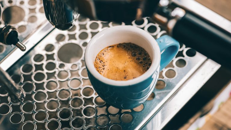 Nahaufnahme einer blauen Espresso-Tasse auf dem Gitter einer Siebtr&auml;germaschine.