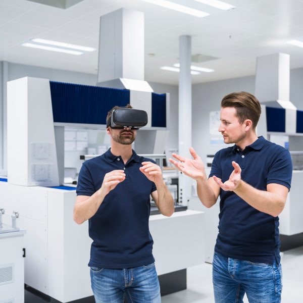 Zwei Personen stehen in einem Tech Lab. Eine der Personen tr&auml;gt ein Headset.