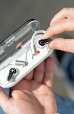 Eine Person h&auml;lt das ge&ouml;ffnete Ladecase der Nothing Ear (open) in einer Hand und nimmt mit der anderen einen der Buds heraus.