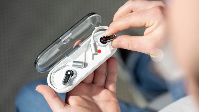 Eine Person h&auml;lt das ge&ouml;ffnete Ladecase der Nothing Ear (open) in einer Hand und nimmt mit der anderen einen der Buds heraus.