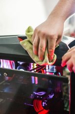 Frühjahrs-Check für deine PC-Hardware, So machst du sie fit Eine Person macht mit einem Tuch einen Gaming-PC sauber, das seitliche Glas ist dabei ausgeklappt.