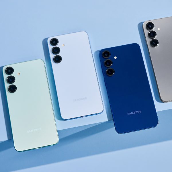 Vier Samsung Galaxy-S25-Handys liegen auf einer blauen Oberfl&auml;che nebeneinander.