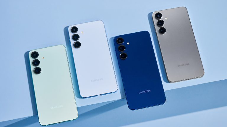 Vier Samsung Galaxy-S25-Handys liegen auf einer blauen Oberfl&auml;che nebeneinander.