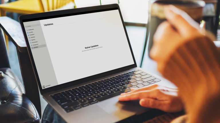 Eine Person sitzt vor einem MacBook Pro und prüft den App Store nach Updates.