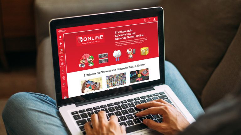 Eine Person sitzt vor einem MacBook Pro, auf dem die Seite von Nintendo Switch Online zu sehen ist.