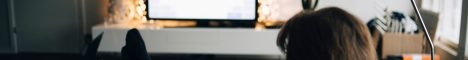 Eine Person sitzt auf einer Couch in einem Wohnzimmer und hält ihr Smartphone quer in den Händen. Auf einem Fernseher vor ihr sieht man den gleichen Inhalt, wie auf dem Smartphone.