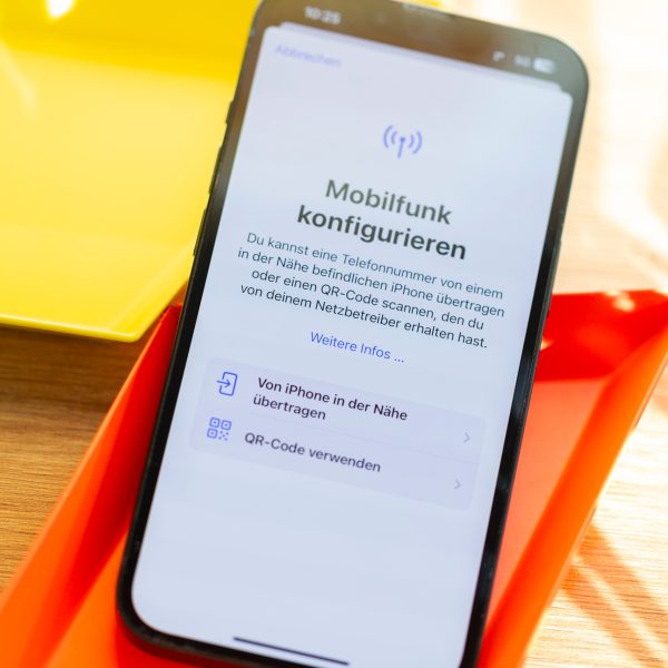 Auf einem iPhone ist die Funktion zu Mobilfunk-Konfiguration geöffnet. Es liegt auf einer bunten Unterlage.
