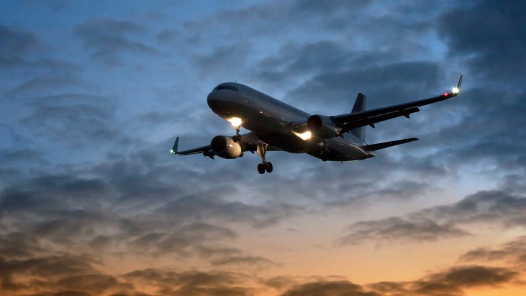 Ein Flugzeug im Landeanflug in der Dämmerung.