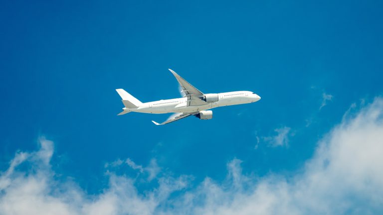 Ein Flugzeug vor blauem Himmel mit leichter, weißer Bewölkung.