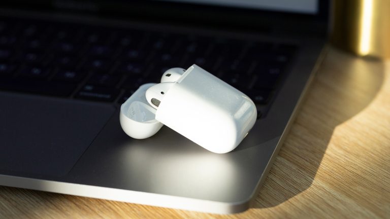 Ein geöffnetes Ladecase mit beiden AirPods darin, liegt auf einem geöffneten MacBook.