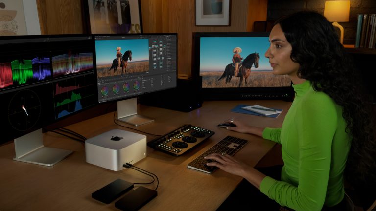 Eine Person sitzt vor drei Monitoren und bearbeitet ein Video auf einem Mac Studio.