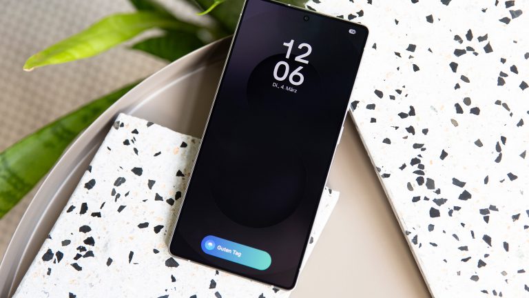 Ein Samsung Galaxy S25 Ultra mit aktivierter Gemini-Funktion auf dem Sperrbildschirm liegt auf einem teilweise marmorierten Untergrund und im Hintergrund ist eine Pflanze zu sehen.