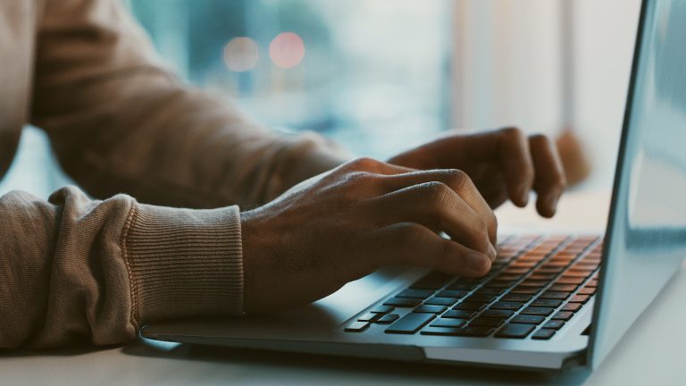Seitenansicht eines ge&ouml;ffneten Notebooks. Die H&auml;nde einer Person liegen auf der Tastatur.