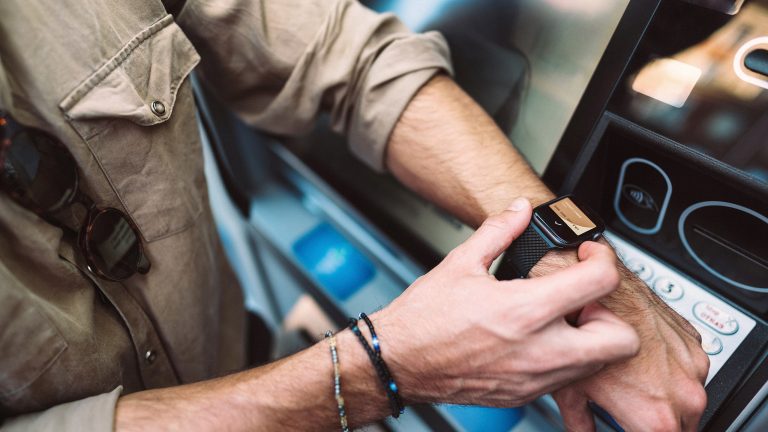 Eine Person h&auml;lt ihre Apple Watch an ein Kartenleseger&auml;t, um damit den Transport im &ouml;ffentlichen Verkehr zu bezahlen.