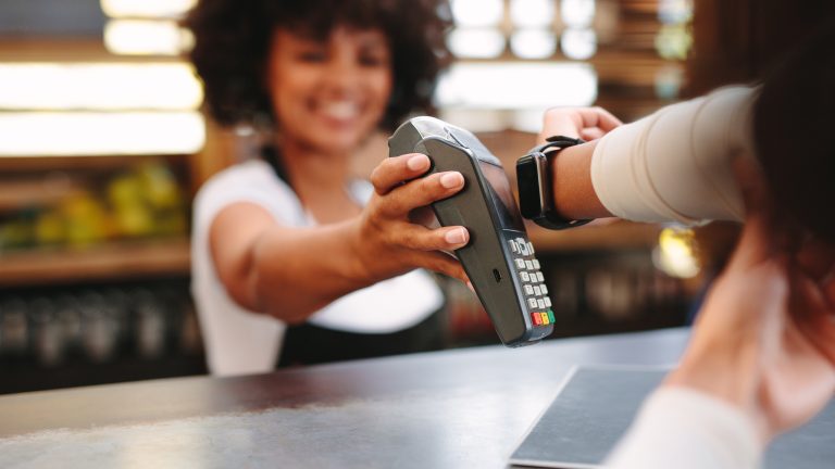 Eine Person h&auml;lt ihre Apple Watch an ein Kartenleseger&auml;t, um per Apple Pay zu bezahlen.