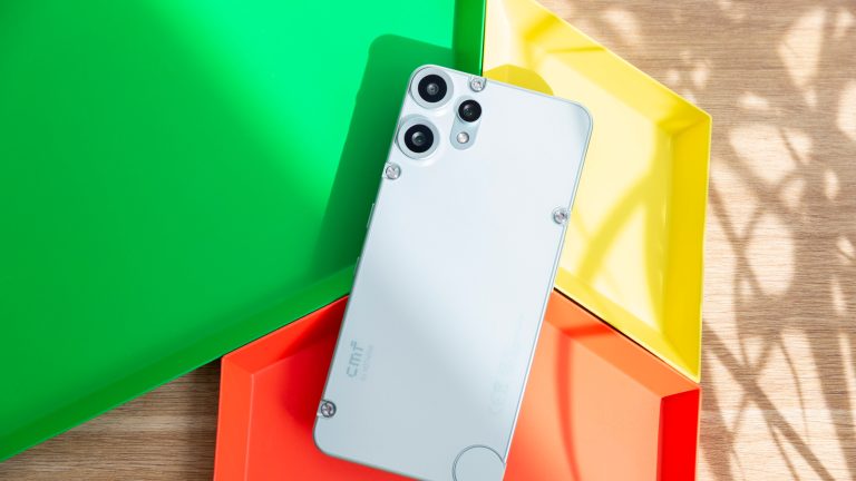 Ein CMF Phone 2 Pro liegt mit der R&uuml;ckseite nach oben auf bunten Schalen.