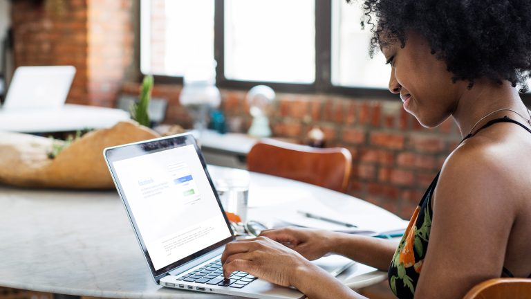 Eine Person sitzt an einem Laptop und hat die Facebook-Anmeldeseite geöffnet.