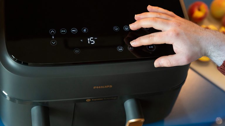 Nahaufnahme des Bedienfelds einer Philips Heißluftfritteuse. Eine Hand drückt einen der Knöpfe.