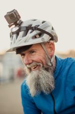 Eine Person tr&auml;gt einen blauen Windbreaker und einen Fahrradhelm auf dem eine Actionkamera befestigt ist.