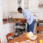 Alt-Text: Eine Person räumt nach dem Frühstück Geschirr in eine Spülmaschine.