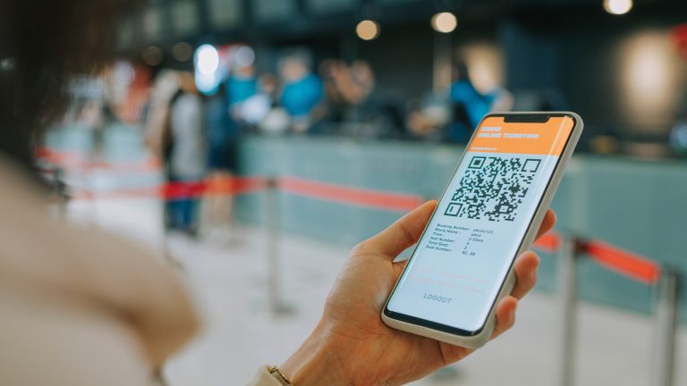 Eine Person hält ein Smartphone in der Hand, auf dem ein QR-Code zu sehen ist.