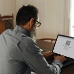 Eine Person sitzt vor einem Laptop und meldet sich bei Telegram Web an.